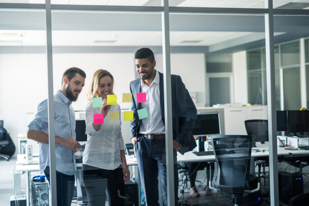 Cropped shot of coworkers using sticky notes on a glass wall during a meeting.